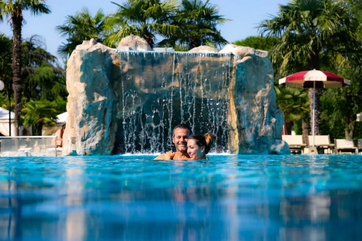Coppia in piscina davanti alla cascata all'Hotel Terme All'Alba